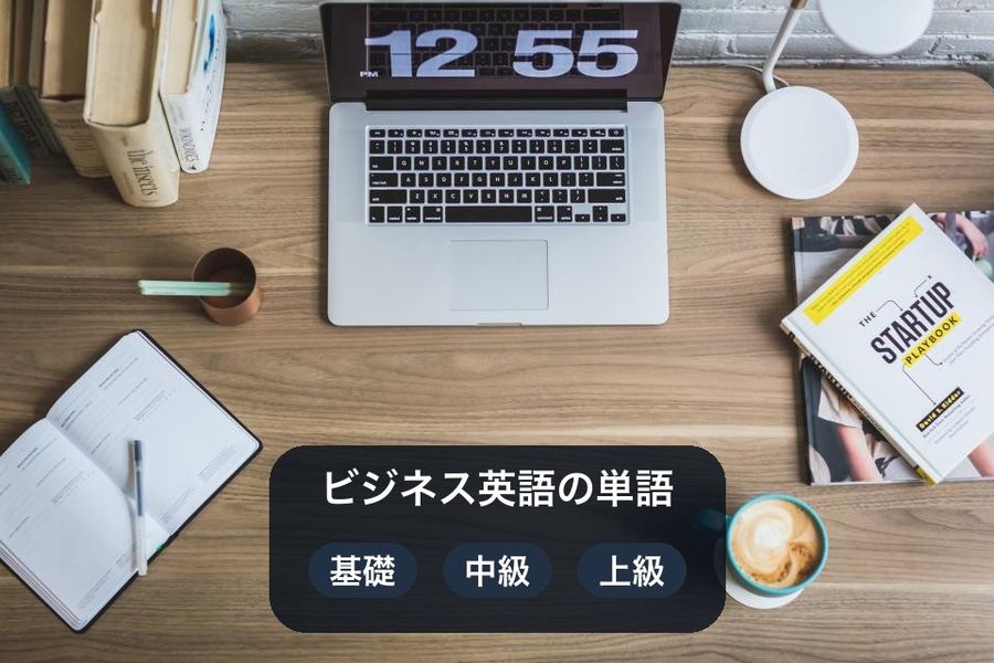 An overhead desk photo with a card over the empty wood naming the three levels of the business vocabulary theme: basic, intermediate, advanced