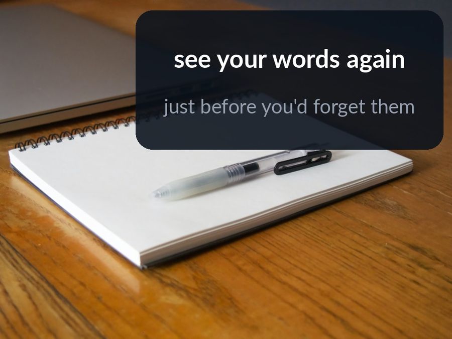 A notebook and pen beside a laptop, with the words ‘see your words again, just before you'd forget them’ over the empty corner of the desk