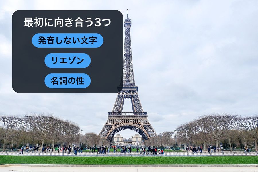 The Eiffel Tower under open sky, with a panel reading '最初に向き合う3つ' (three things to face first) over three pills: 発音しない文字 (silent letters), リエゾン (liaison), 名詞の性 (noun gender)