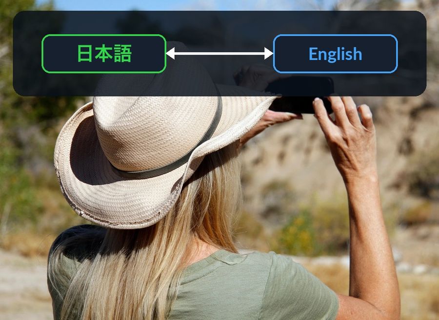 A photo of someone taking a picture on their iPhone outdoors, with a dark band across the sky showing a 日本語 (Japanese) pill and an English pill joined by a two-way arrow