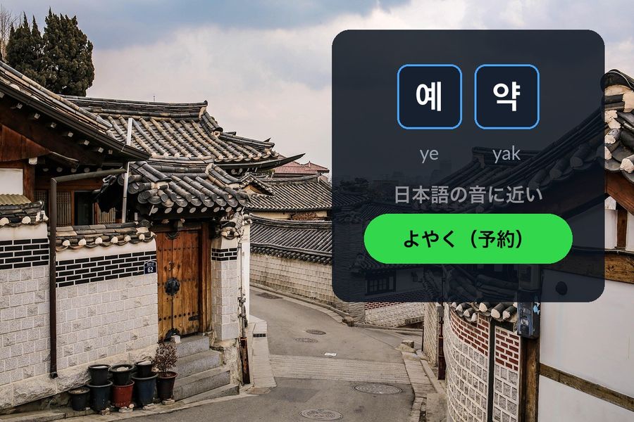 Bukchon Hanok Village in Seoul at dusk, with the Korean word 예약 (reservation) written in the sky next to よやく（予約）, the Japanese on'yomi reading it echoes