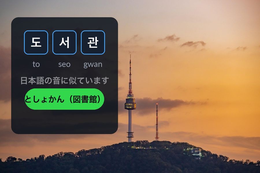 N Seoul Tower at dusk, with the Korean word 도서관 (library) written in the sky next to としょかん, the Japanese on'yomi reading it echoes