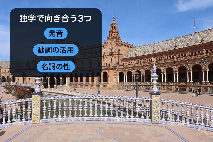 Seville's Plaza de España under open sky, with a panel reading '独学で向き合う3つ' (three points to work on) over three pills: 発音 (pronunciation), 動詞の活用 (verb conjugation), 名詞の性 (noun gender)