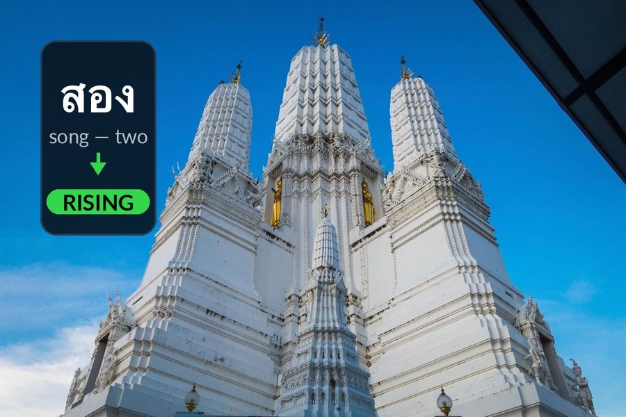 A white Bangkok temple prang with the article's own example added: สอง (song, two) takes the rising tone