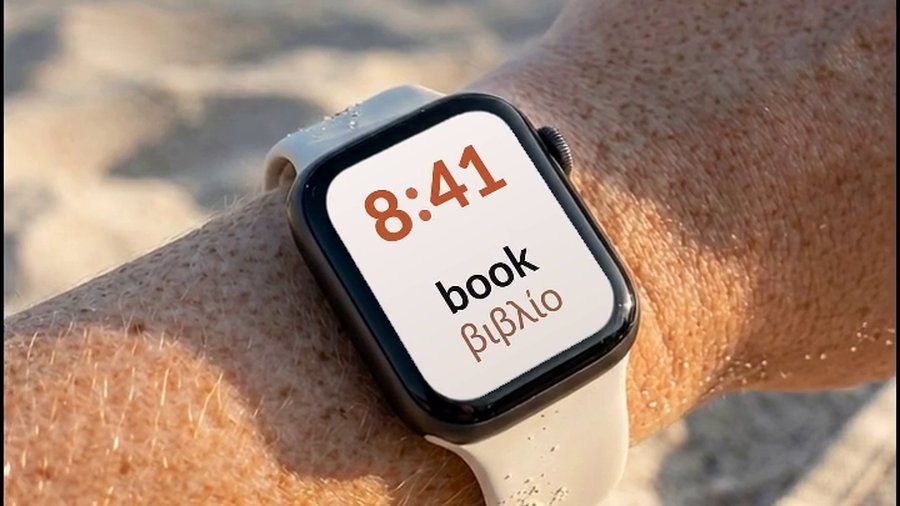Ένα Apple Watch στον καρπό σε παραλία, με την αγγλική λέξη book και την ελληνική της μετάφραση, βιβλίο