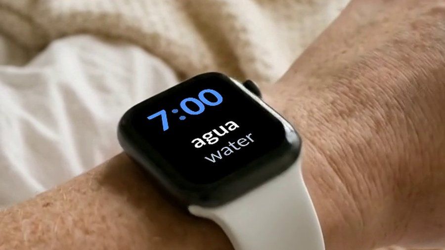 An Apple Watch in bed, showing a Spanish word and its English translation on the watch face