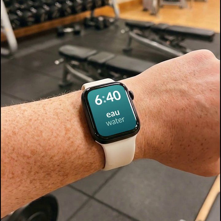 An Apple Watch at the gym, showing a French word and its English translation on the watch face