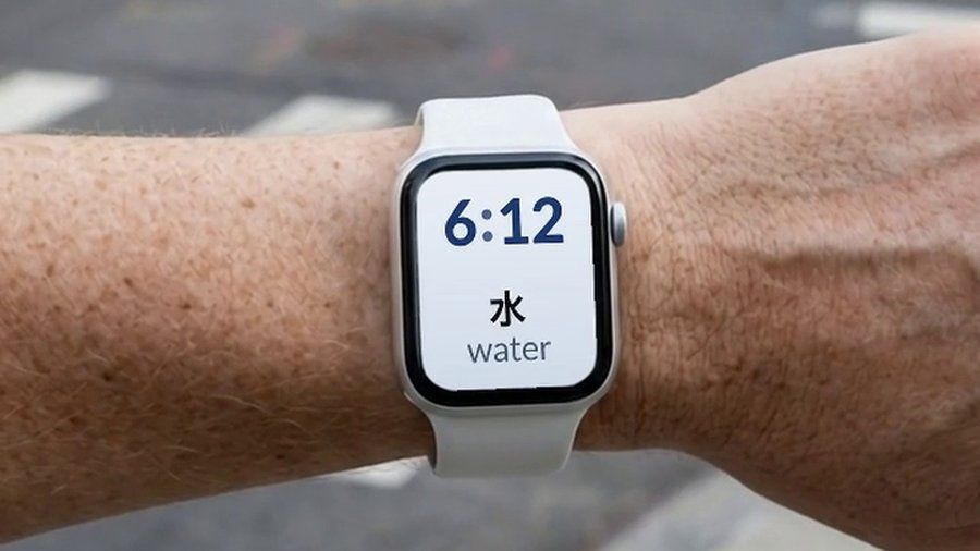 An Apple Watch in the street, showing a Japanese word and its English translation on the watch face