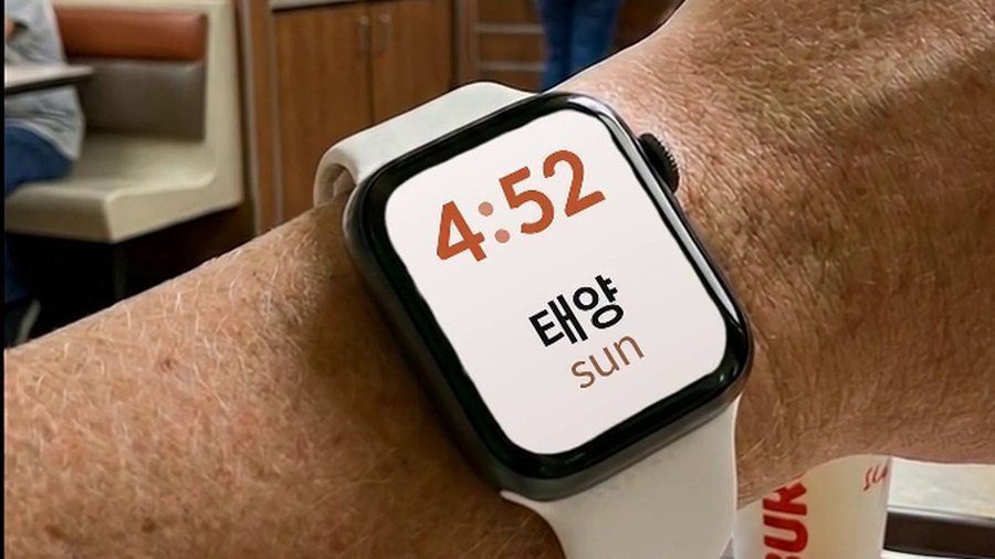 An Apple Watch in a fast-food restaurant, showing a Korean word and its English translation on the watch face