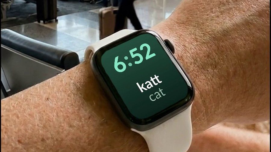 An Apple Watch at an airport, showing a Norwegian word and its English translation on the watch face