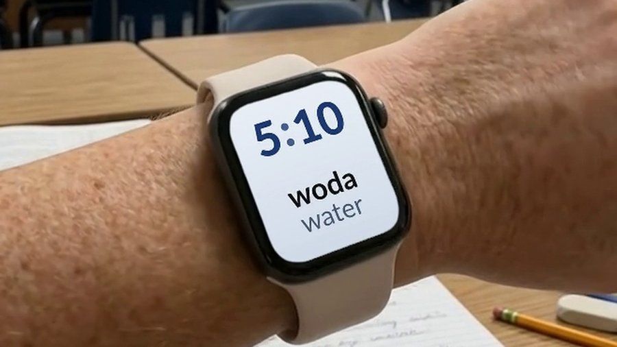 An Apple Watch in a classroom, showing a Polish word and its English translation on the watch face