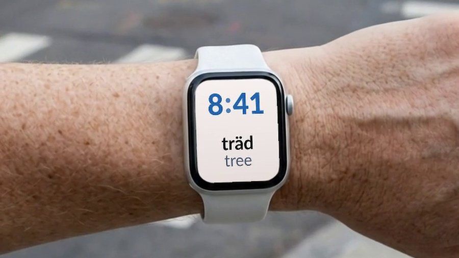 An Apple Watch in the street, showing a Swedish word and its English translation on the watch face