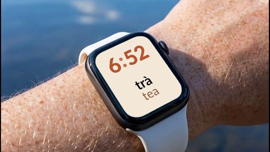 An Apple Watch by a lake, showing a Vietnamese word and its English translation on the watch face