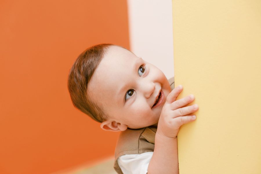 A smiling baby peeking out from behind a wall