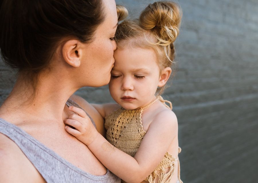 A mother kissing her young daughter on the cheek