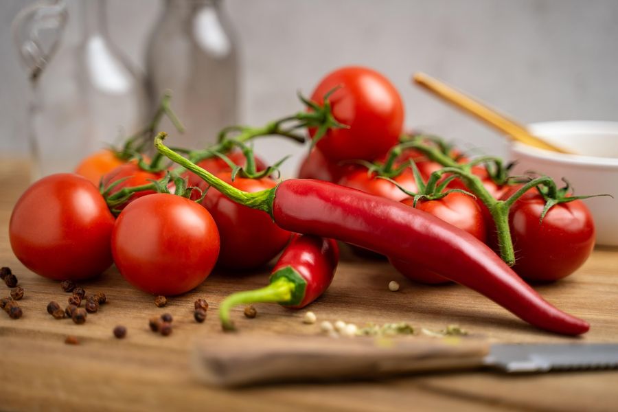 Tomatoes and a red chili on a wooden board