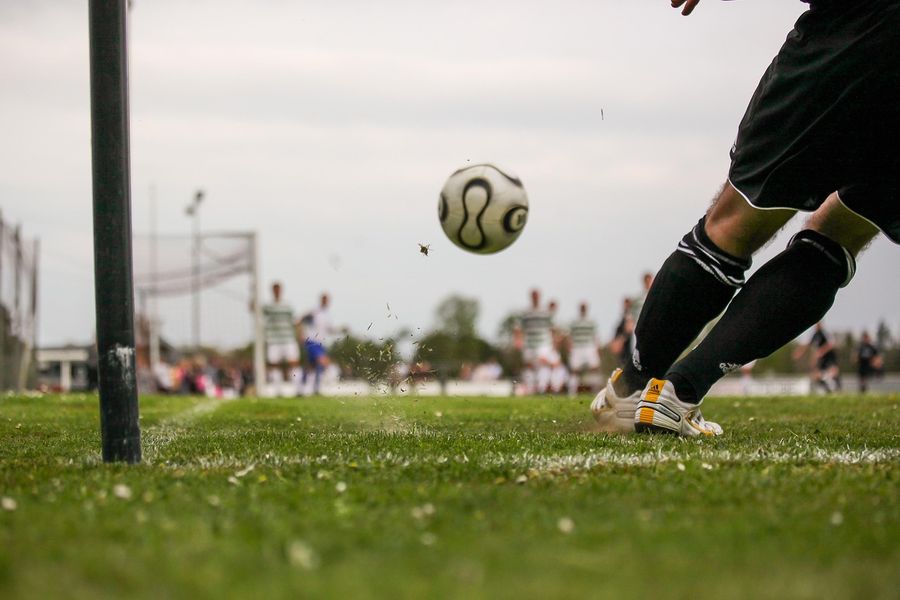 A footballer kicking a ball on a grass pitch