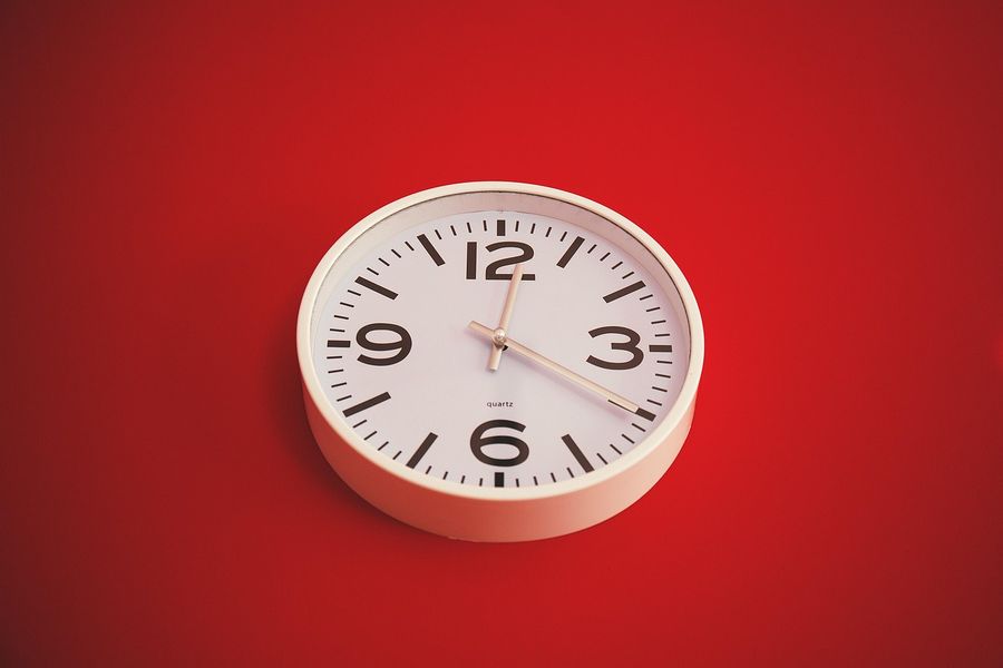A round white wall clock on a red background