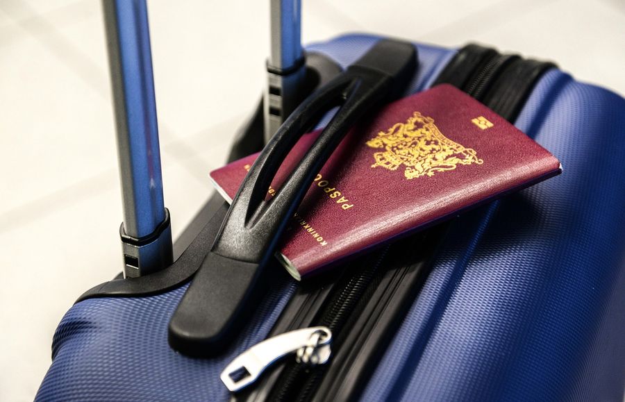 A passport resting on a blue suitcase